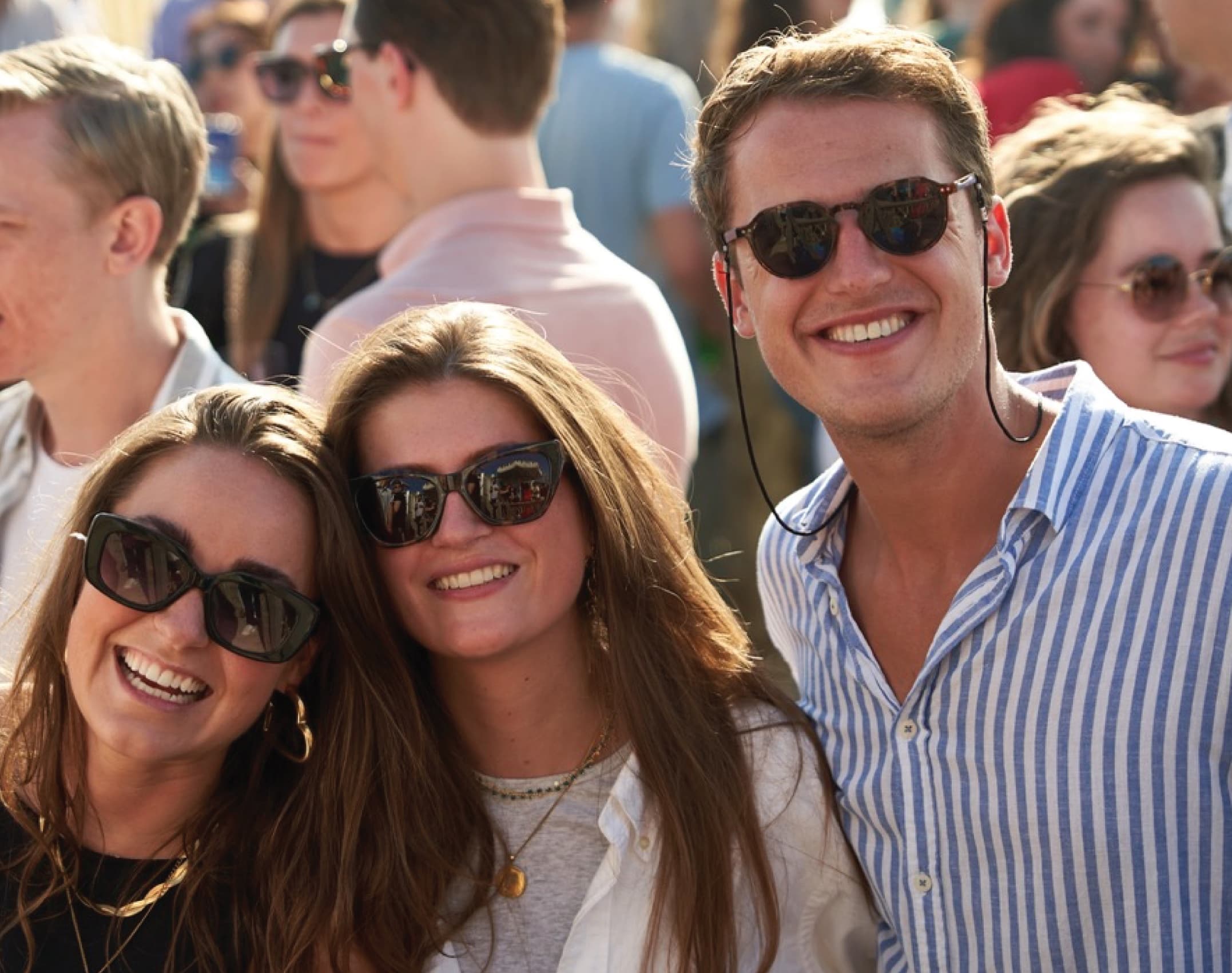 Three friends close together in golden light at a festival.